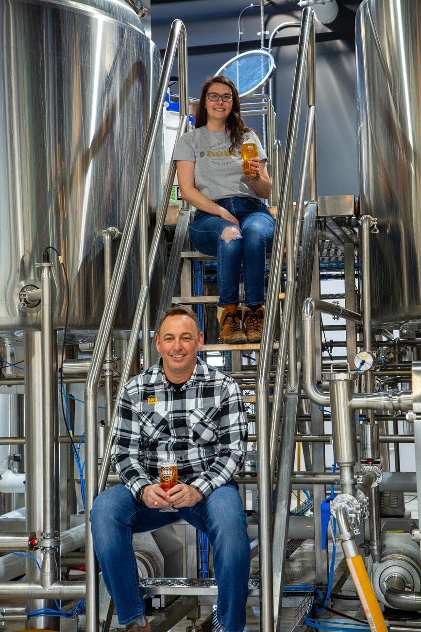 Mike McKelvin and a brewery employee sit by the brewing vats.