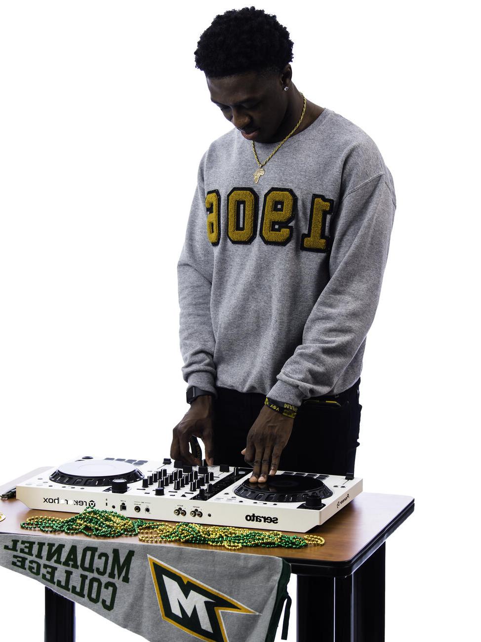 Kekuta呸 poses with a DJ board on a table.