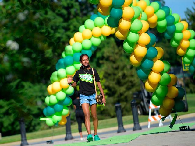 student walks under balloon arch