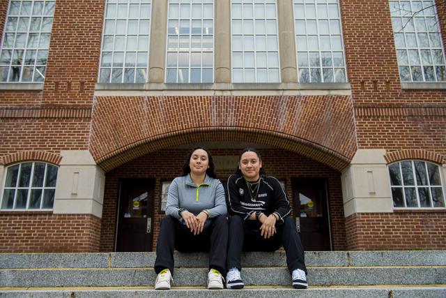 A pair of twins sits outdoors on the steps in front of 金沙js6038's Hoover Library.