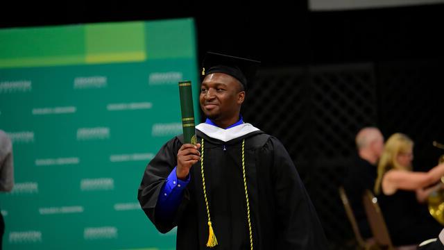 Student with diploma in hand at Commencement 2019.